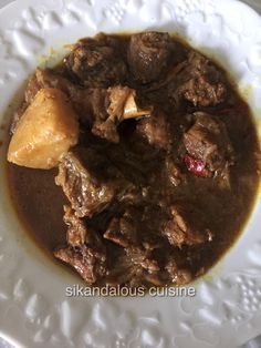 a white plate topped with meat and potatoes covered in gravy on top of a table