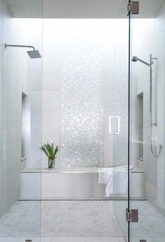 a bathroom with a glass shower door and white tile flooring, along with a plant in the corner