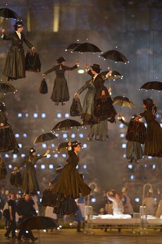 several women in dresses and umbrellas are suspended from the ceiling at a fashion show