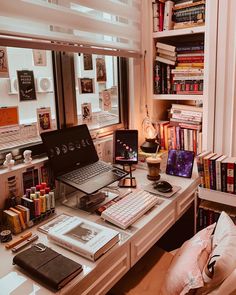 a laptop computer sitting on top of a desk next to a book shelf filled with books