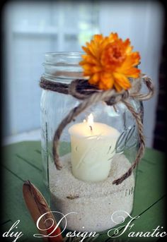 a glass jar filled with sand and a lit candle