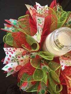 a red and green christmas wreath with a mason jar