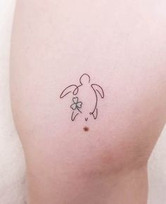 a small turtle tattoo on the back of a woman's left thigh, with a clover