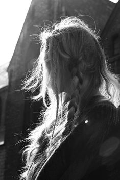 a woman with long hair standing in front of a building