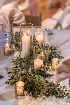 candles and greenery are arranged on the table