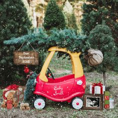 a red toy car sitting in the middle of a christmas tree lot with presents on it