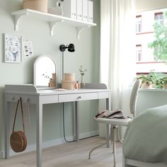 a desk with a mirror, lamp and other items on it in a room that has light green walls