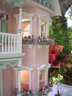 a pink doll house with flowers in the windows and balconies on the second floor