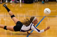 a female volleyball player dives for the ball