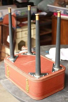 a suitcase sitting on top of a table with four black candles sticking out of it