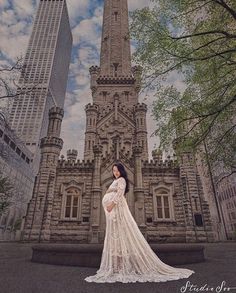 a woman is standing in front of a tall building with a clock tower on it's side