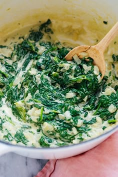 spinach and cheese in a pot with a wooden spoon