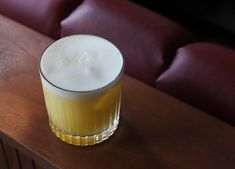 a close up of a drink on a table with a red couch in the background