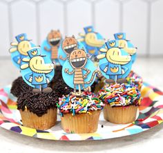 cupcakes decorated with cartoon characters and sprinkles on a paper plate