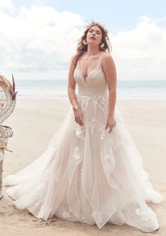 a woman in a wedding dress standing on the beach