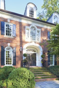 a large brick house with black shutters and white trim on the front door is shown