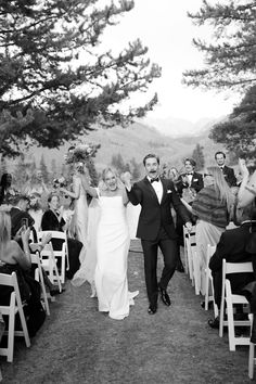 a bride and groom walk down the aisle after their wedding ceremony in black and white