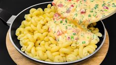 macaroni and cheese is being served in a skillet with a wooden spoon