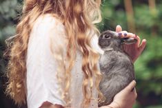 a woman holding a small rabbit in her hands