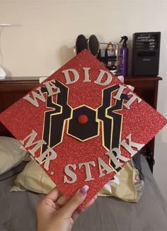 someone is holding up a red graduation cap