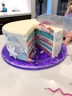 someone is holding a knife to cut into a multi - layer cake on a purple plate