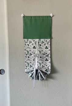 a green and white curtain hanging on the wall next to a door with a bow