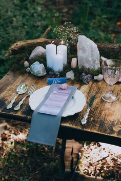 the table is set with candles, plates and napkins for an outdoor dinner party