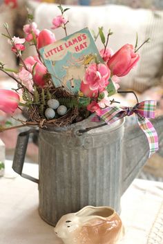 a watering can filled with pink flowers and eggs