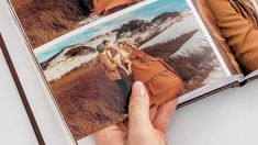 a person is holding an open book with pictures on it in front of the camera