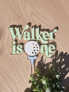 a wooden sign that says walker is one with a golf ball on it next to a potted plant