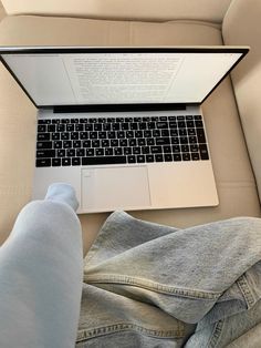 an open laptop computer sitting on top of a couch next to someone's feet