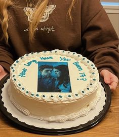 a woman holding a cake with an image on the frosting in front of her