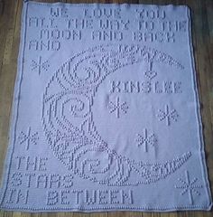 a white crocheted blanket with words and numbers on the front, sitting on a wooden floor