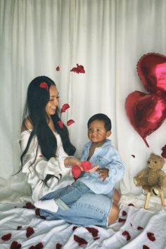 a woman and child sitting on a bed with hearts flying in the air behind them