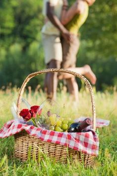 an image of a man and woman in the grass with a basket full of fruit