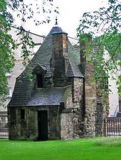 an old stone building with a steeple on the top and green grass in front