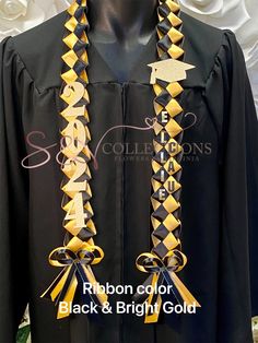 a black and yellow graduation gown with ribbons on the front, and gold letters on the back