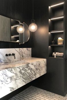 a bathroom with marble counter tops and black walls, along with two lights hanging from the ceiling