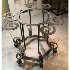 an iron table with four circular glass tables on wheels, sitting on a tiled floor