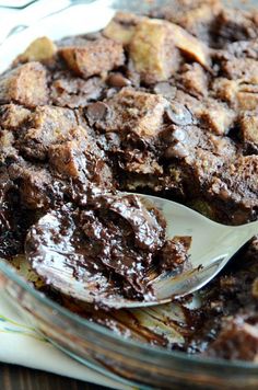 a close up of a pie on a plate with a spoon in it and chocolate topping