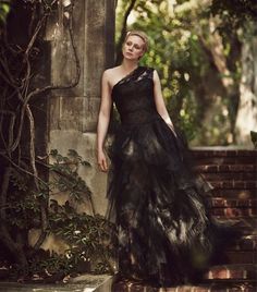 a woman in a black dress standing on some steps