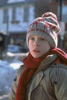 a young boy wearing a red and white knitted hat, scarf, and jacket