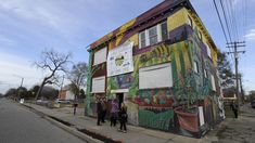 some people are standing in front of a building that has been painted with many colors