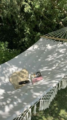 a white hammock sitting on top of a grass covered field next to trees