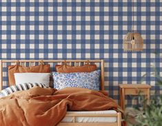 a bed with blue and white checkered wallpaper next to a wooden night stand