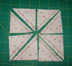 four pieces of fabric are laid out on a green cutting board with scissors and thread