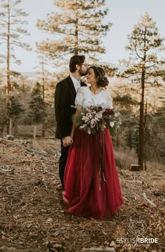 a bride and groom are standing in the woods