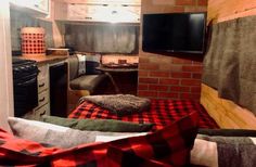 a living room filled with furniture and a flat screen tv mounted to the wall next to a brick wall