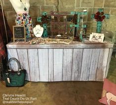 a table with many items on it in front of a brick wall and two mannequins