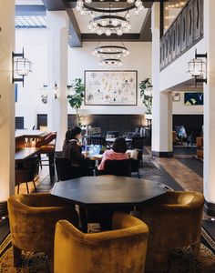 two people sitting at a table in a large room with chandeliers hanging from the ceiling